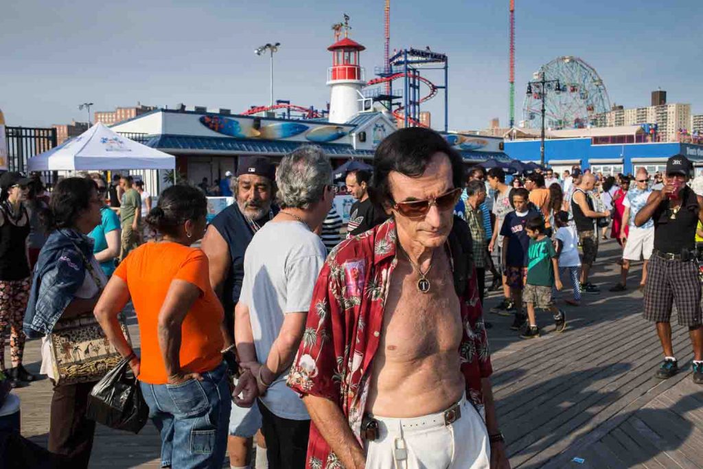 A a man in the crowd on the Coney Island boardwalk.