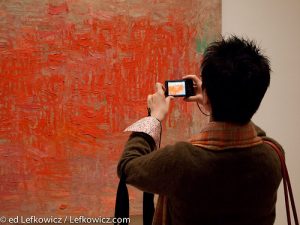 A museum visitor photographing a painting