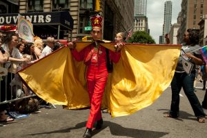 A marcher costumed in a red suit and a cape with a bright yellow lining n the 2011 Pride Parade on New York's Fifth Avenue.