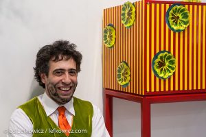 Bart Niswonger sitting next to one of his colorful cabinets