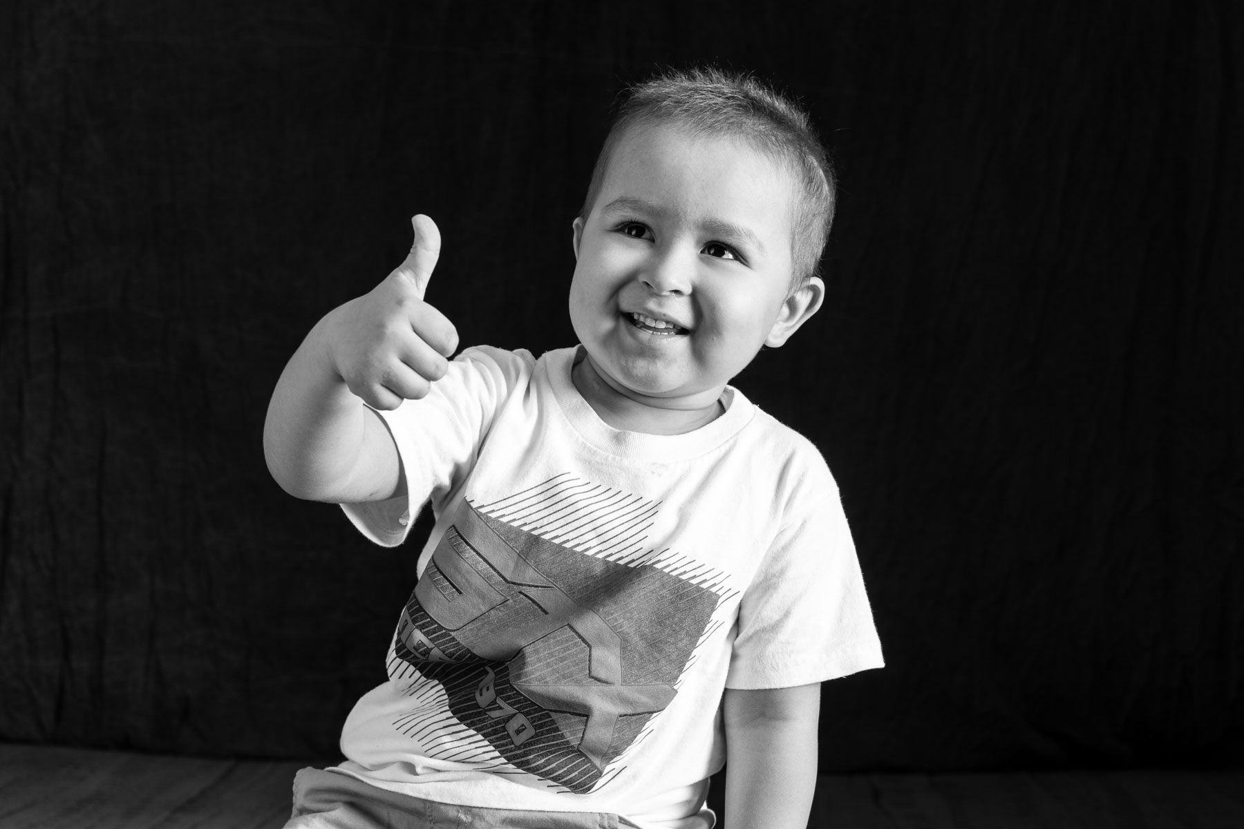 Black and white photo of a young boy giving a thumbs-up
