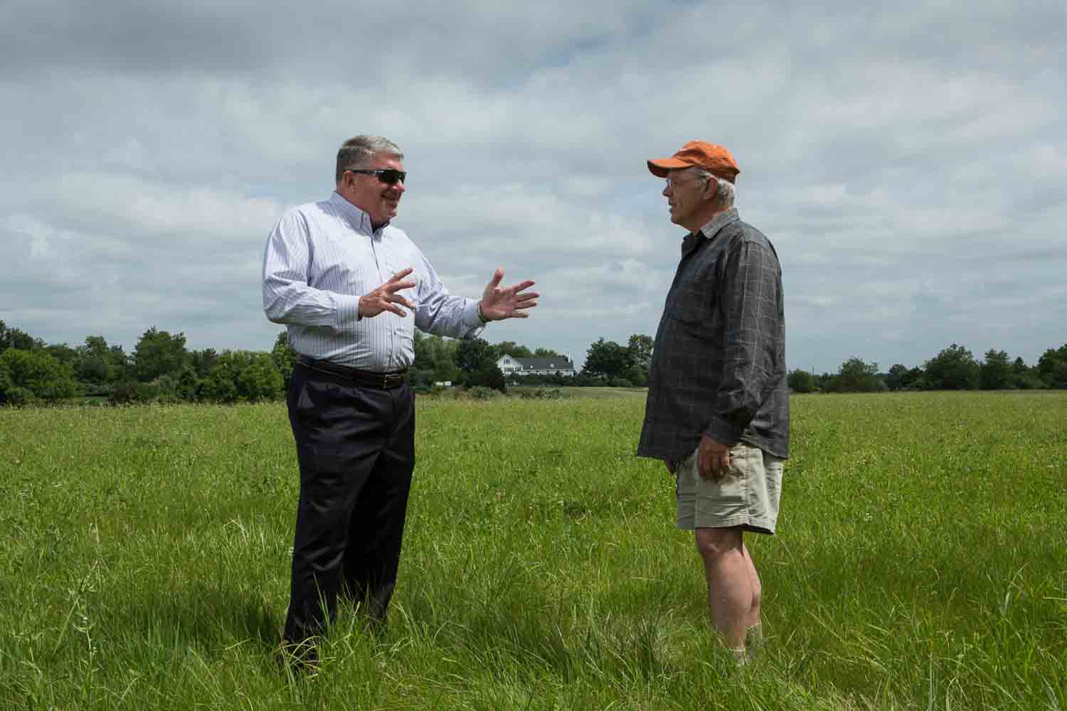 A financial advisor and his client in a field photographed for a financial services firm.