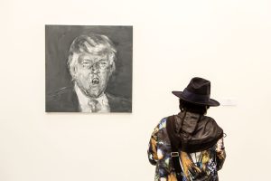 A woman visitor to the Frieze Art Fair looks at a painting of a screaming president-elect Donald Trump by Yan Pei-Ming in the Galerie Thaddaeus Ropac.