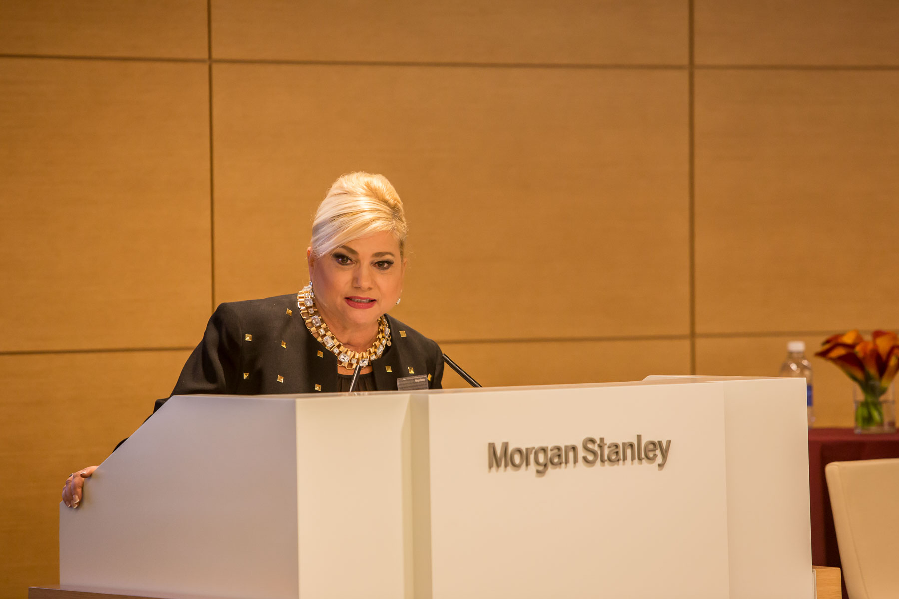A woman speaking at a lectern with a Morgan Stanley logo.