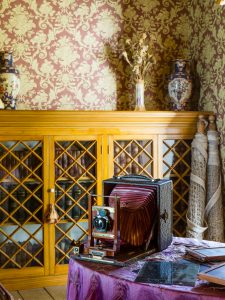 The living room in the Alice Austen house, with an old camera and photographic plates on the table.