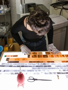 A woman examining photographic negatives at work in the Bushwick Community Darkroom.