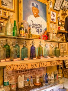 Displays of seltzer bottles and a painting of Jackie Robinson in The City Reliquary.