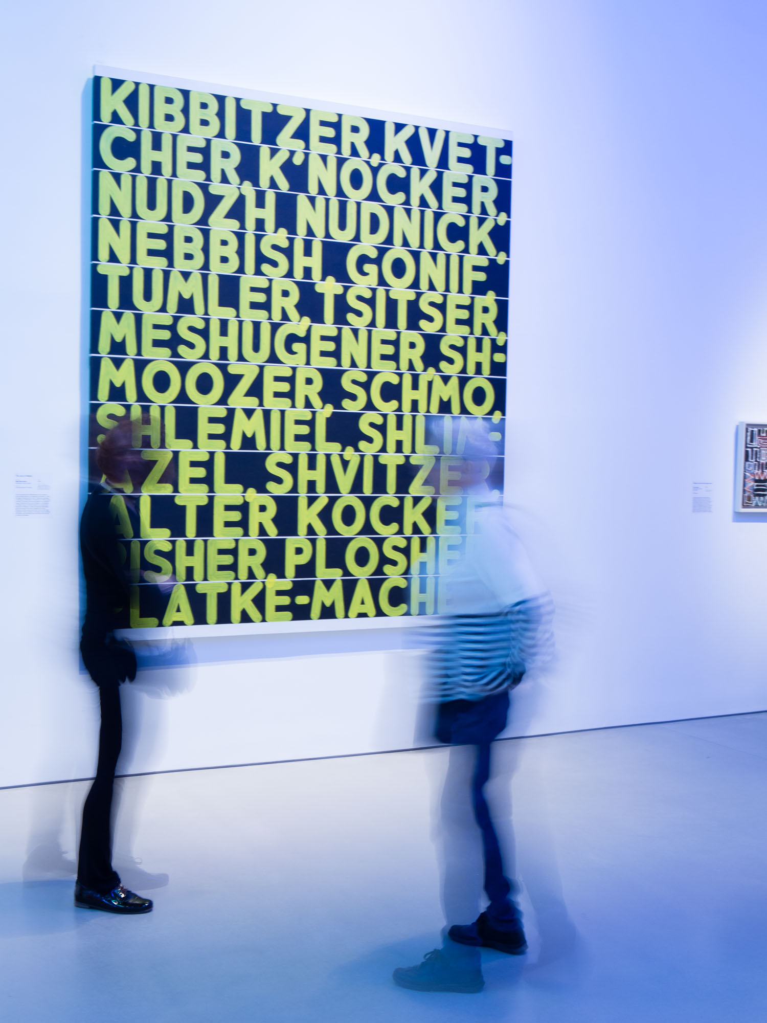 Blurred visitors look at Mel Bochner's painting "The Joys of Yiddish" in the Jewish Museum.