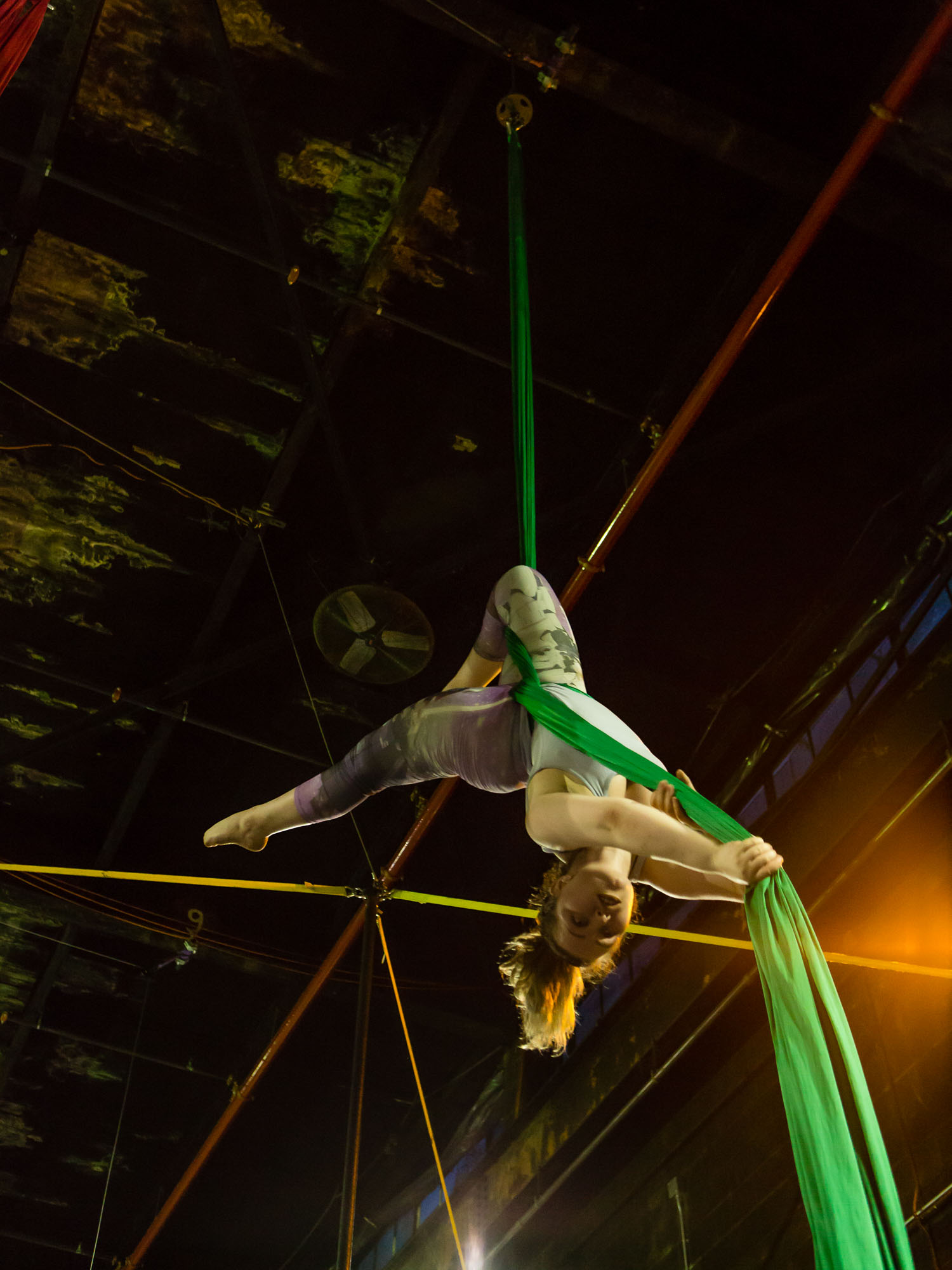 An acrobatic woman upside down on the aerial silks at The Muse.