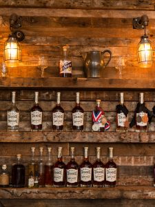 The tasting room of the Van Brunt Stillhouse in Brooklyn's Red Hook neighborhood, bottles of their whiskeys on rough wood shelves.
