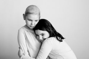Two girls, one with hair loss from chemotherapy, Photographed for Flashes of Hope.