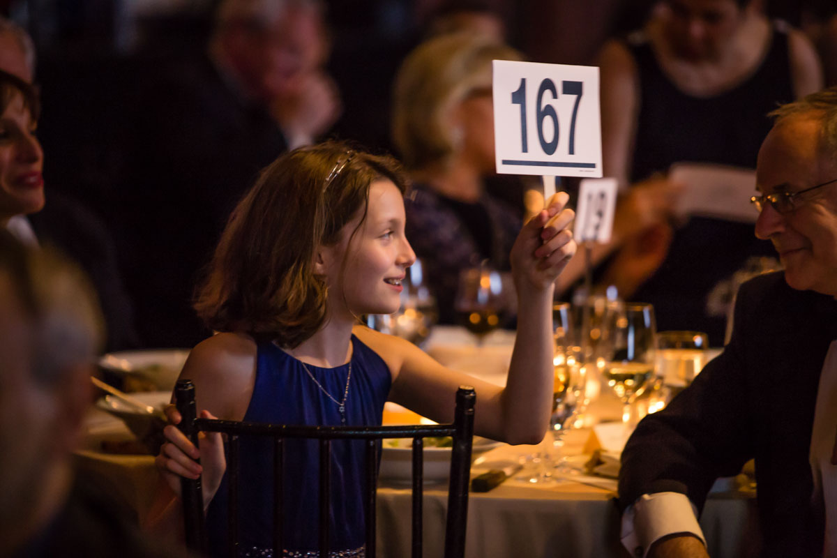 A girl bids for her family at the New York Pops gala
