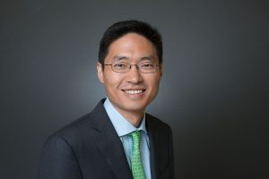 Portrait of a smiling Asian man against a gray background