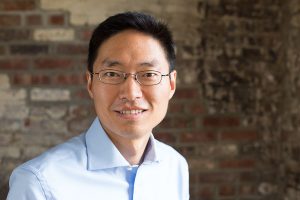 Portrait of a smiling Asian man against a distressed brick wall