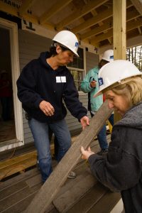 Women in hard hats assembling a deck for a house built by Habitat for Humanity