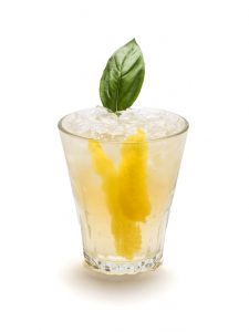 Glass with basil bourbon mule with lemon and basil garnish