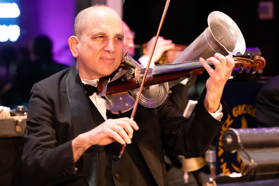 A musician playing a Stroh horn violin at a gala for the New York Pops.
