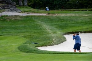 Photo of a golfer blasting out of a bunker